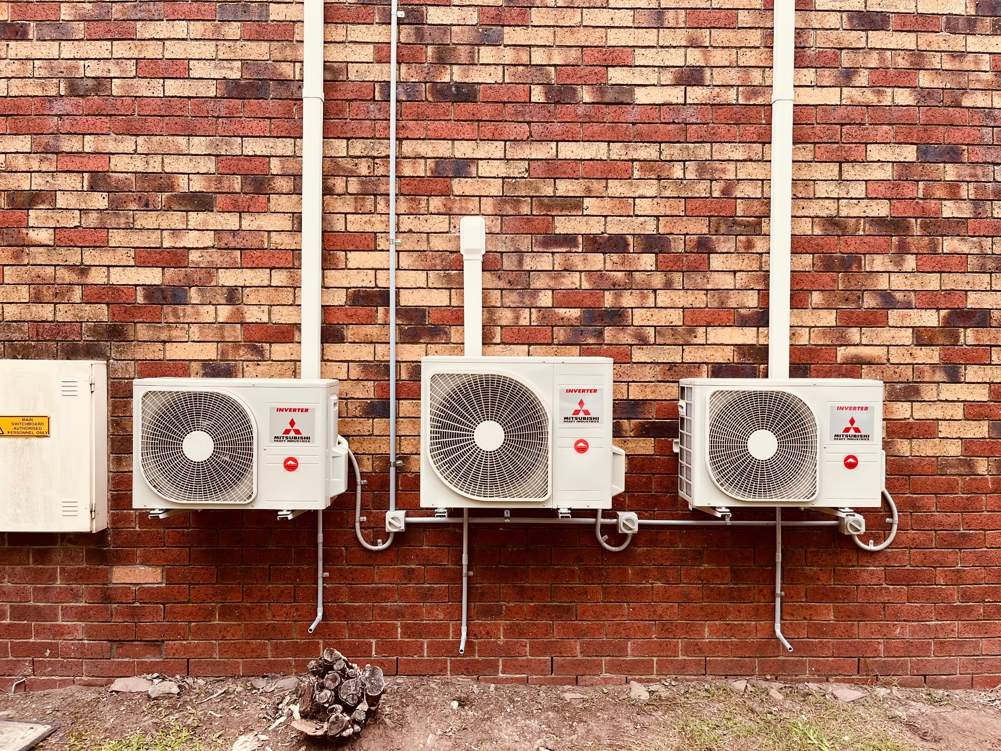 Three split-system outdoor units installed neatly on a brick wall by Swind